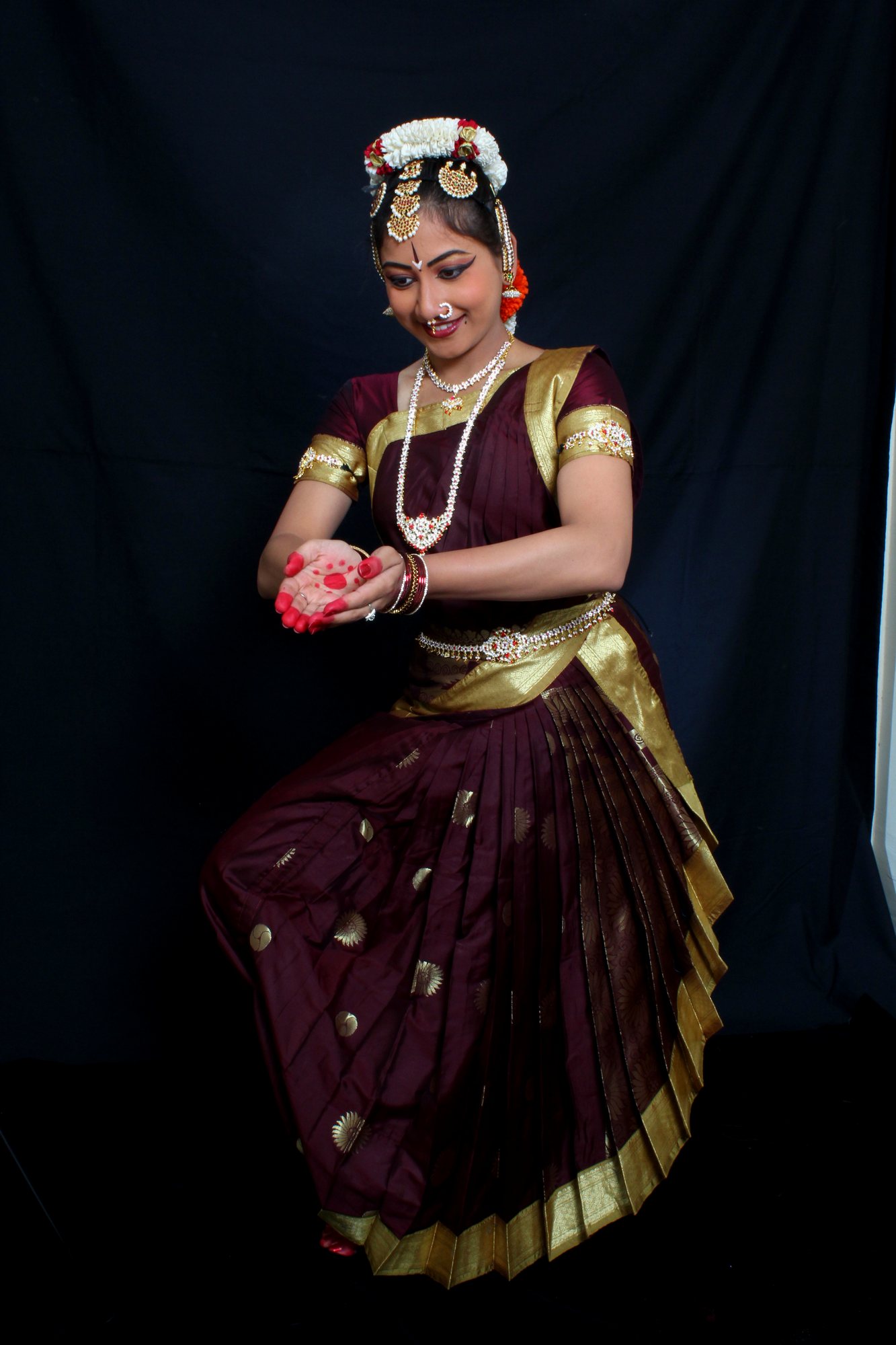 Seated Bharatanatyam pose with fanned pleats and a flower