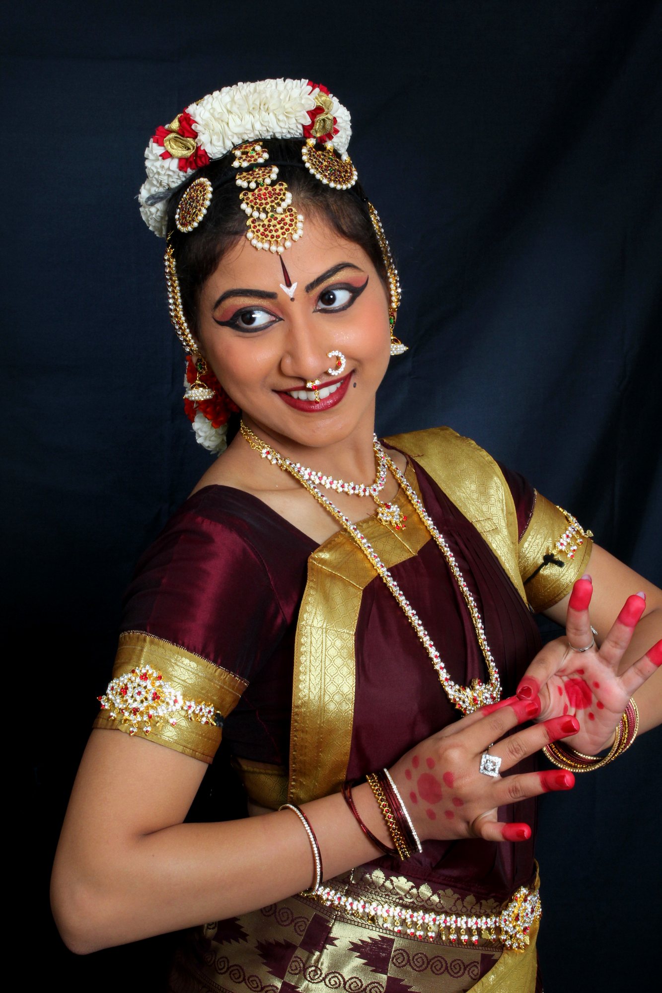 Bharatanatyam hand gesture held beside a smile