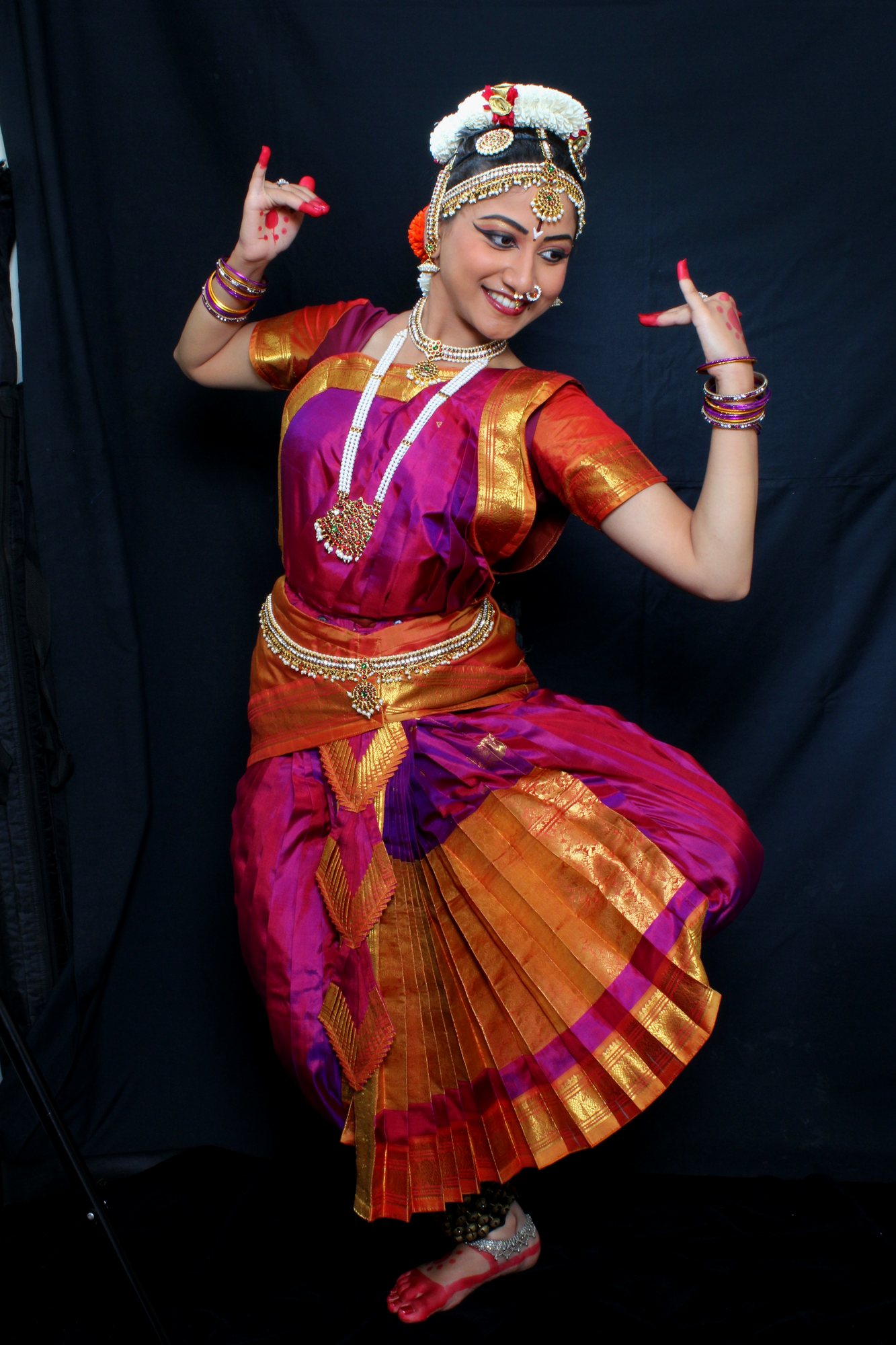 Standing Bharatanatyam pose with raised hand gestures