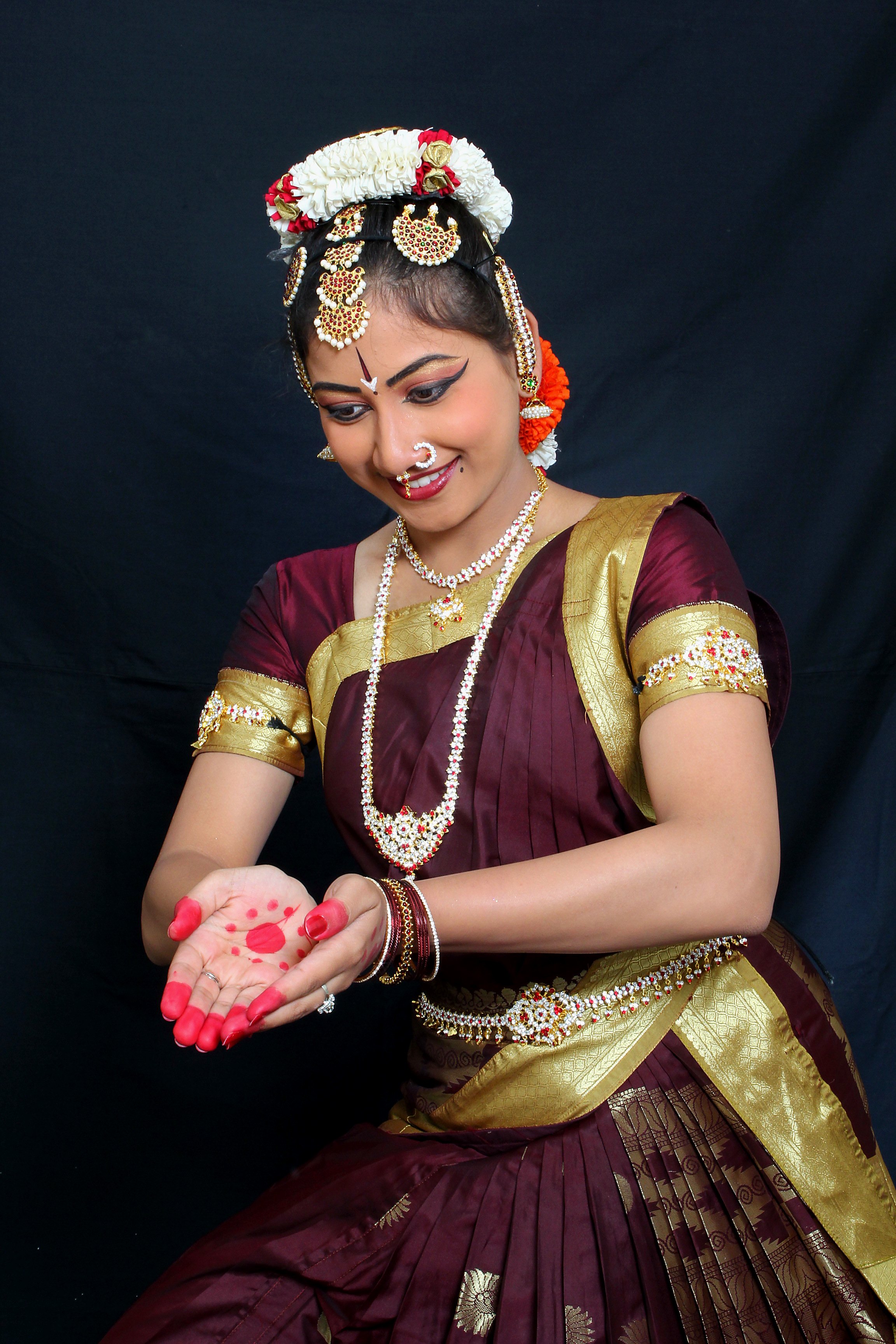 A dancer studies a flower held in both palms